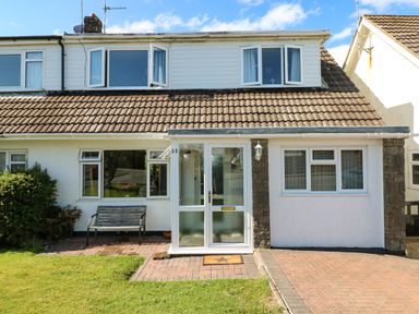 A front view of a semi detached house with a tiled roof a porch a driveway and a bench at 53 St Brides View Roch