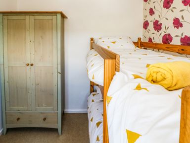 A bedroom with wooden bunk beds and a wooden wardrobe at 53 St Brides View in Roch