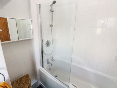 A bathroom with a bathtub shower combination glass shower screen and wall-mounted mirrored cabinet at 53 St Brides View in Roch