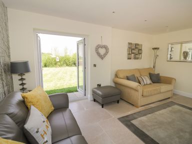 A living room with two sofas cushions and an open door to a garden at Garden Cottage in Upton Upon Severn
