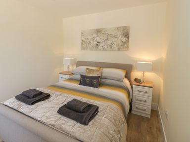 A bedroom with a double bed striped bedding bedside tables lamps and towels at Garden Cottage in Upton Upon Severn