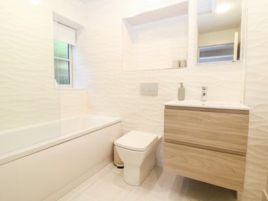A bathroom with a bathtub toilet and a wooden vanity with sink at 12 Manor Farm Close in Kingham
