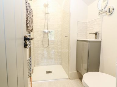 A bathroom with a walk in shower a towel rack a sink with cabinet and a toilet at 12 Manor Farm Close Kingham