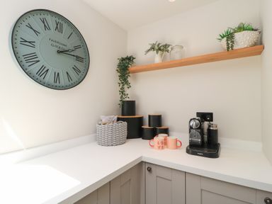 A kitchen corner with clock, shelf, coffee machine, and mugs at 12 Manor Farm Close Kingham