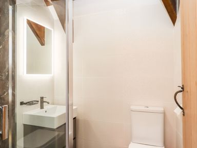 A bathroom with a sink and illuminated mirror next to a toilet at Bagtor Granary in Ilsington