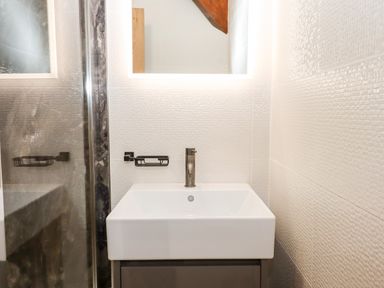 A bathroom sink with a faucet and a mirrored wall at Bagtor Granary in Ilsington