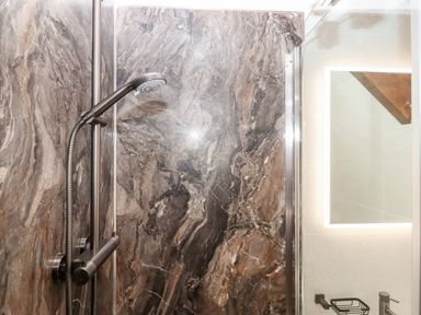 A shower area with a handheld showerhead and dark marbled wall at Bagtor Granary in Ilsington