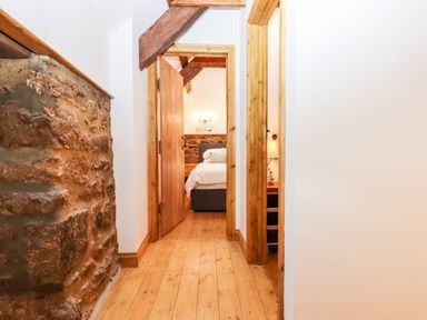 A hallway with wooden floor and doors leading to bedrooms at Bagtor Granary in Ilsington
