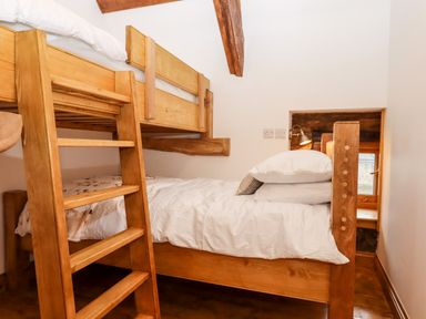 A wooden bunk bed with white bedding in a small room with wooden beams at Bagtor Granary in Ilsington