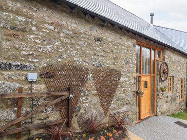 An exterior view of a stone building with a wooden door and windows at Bagtor Granary in Ilsington