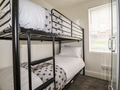 A bedroom with a metal bunk bed next to a window with blinds at Penmar in Looe