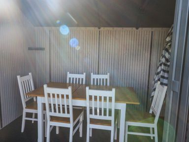 A dining table with six chairs inside a room with paneled walls and an umbrella in the corner at Penmar in Looe
