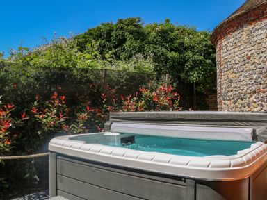 An outdoor hot tub surrounded by plants and a stone wall at Filbert Pod in Arundel West Sussex