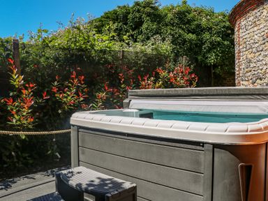 An outdoor hot tub with a small step in a garden setting at Filbert Pod in Arundel West Sussex