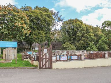 An outdoor swimming pool enclosed by a wooden fence with chairs around it and trees in the background at 60 Valley Lodge Callington near Gunnislake