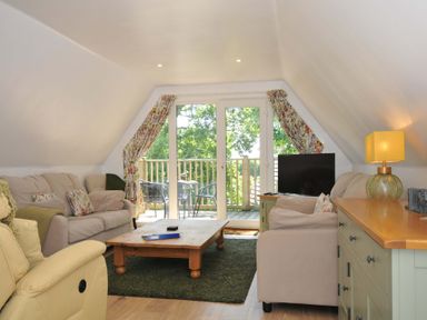 A living room with sofas a coffee table a television and sliding doors leading to a balcony at 60 Valley Lodge in Callington near Gunnislake