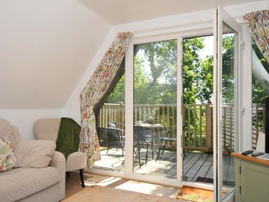 A living room with glass doors opening to a balcony with table and chairs at 60 Valley Lodge Callington near Gunnislake