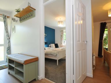 A hallway with a bench and coat hooks leading to two bedrooms at 60 Valley Lodge in Callington near Gunnislake