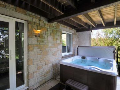 A covered outdoor area with a hot tub and stone wall at 60 Valley Lodge in Callington near Gunnislake