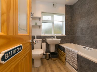 A bathroom with a toilet sink bathtub and window at Chynance in Porthcurno