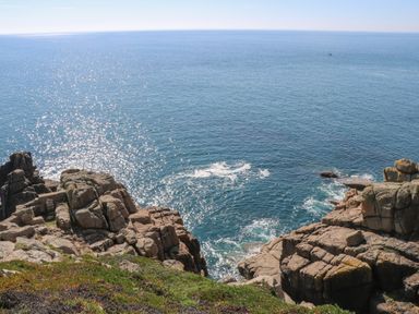 A coastal scene with rocky cliffs and ocean water at Chynance in Porthcurno