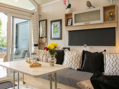 A seating area with cushions a table with flowers and a tray near glass doors at Jacobs Meadow Pod 2 in Minsterley near Chirbury