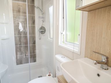 A bathroom with a shower enclosure a toilet and a sink at Burlees Nest in Brigham near Great Broughton Cockermouth