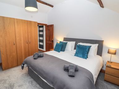A bedroom with a double bed pillows bedside tables a wardrobe and a door at Fryston Cottage in Keswick