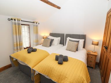 A bedroom with two single beds with yellow bedcovers and grey headboards at Fryston Cottage in Keswick