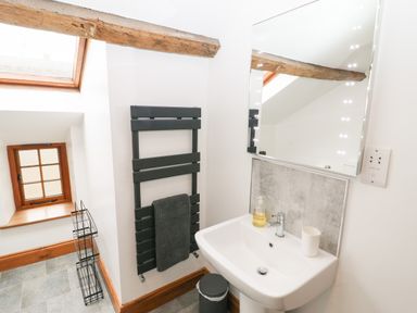 A bathroom with a sink, mirror, towel rack, and skylight window at Fryston Cottage in Keswick