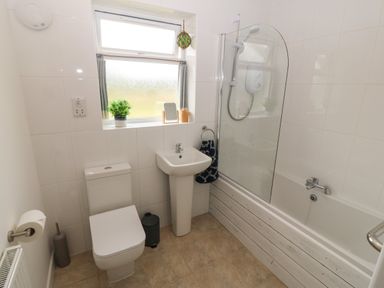 A bathroom with a toilet sink bathtub and window at Cae Berllan in Mynytho near Pwllheli