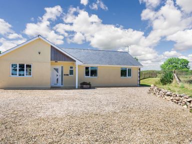 A single-story house with a gravel driveway and small garden at Cae Berllan in Mynytho near Pwllheli