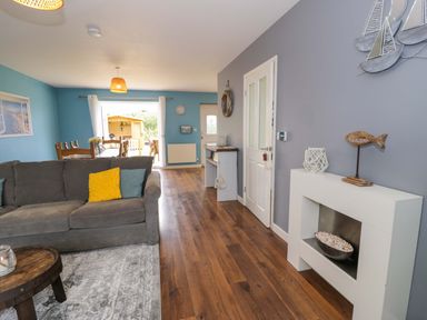 A living room with a sofa and dining area at Cae Berllan in Mynytho near Pwllheli