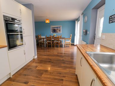 A kitchen with oven and dining area at Cae Berllan in Mynytho near Pwllheli