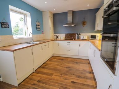 A kitchen with cabinets and appliances at Cae Berllan in Mynytho near Pwllheli
