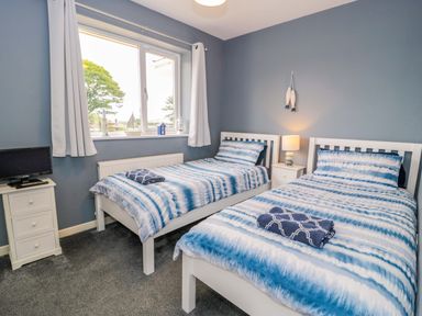 A bedroom with two beds and a television at Cae Berllan in Mynytho near Pwllheli