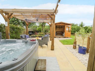 A garden with a hot tub and seating area at Cae Berllan near Pwllheli