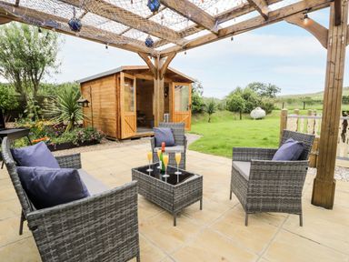 An outdoor seating area with chairs and table at Cae Berllan Mynytho near Pwllheli