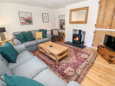 A living room with gray sofas green and yellow cushions wooden coffee table and a fireplace at Widgeons Keel in Flushing