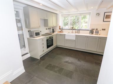 A kitchen with grey cabinets a farmhouse sink and window looking outside at Widgeons Keel in Flushing