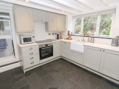 A kitchen with gray cabinets a built in oven microwave white sink and large window overlooking garden at Widgeons Keel in Flushing