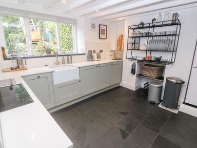 A kitchen with a large window over a sink cabinets countertop and open shelves with dishes at Widgeons Keel in Flushing