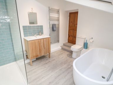A bathroom with a freestanding bathtub a toilet a wooden vanity and a walk in shower at Widgeons Keel in Flushing