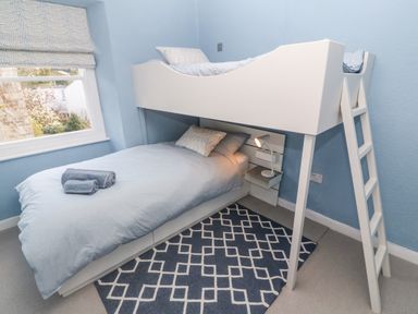 A bedroom with a bunk bed a ladder a window with blinds and a patterned rug at Widgeons Keel in Flushing