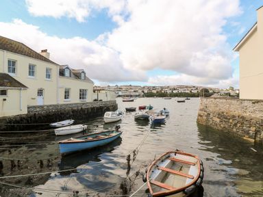 Small boats moored in a harbor next to stone and cream buildings with a town in the distance at Widgeons Keel in Flushing