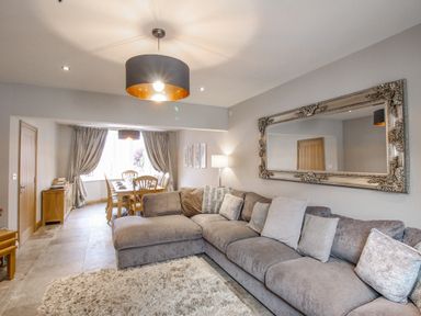A living room with a large gray sectional sofa and a dining area with wooden chairs at Family House in Weymouth