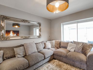 A living room with a large gray sectional sofa and a mirror above it at Family House in Weymouth