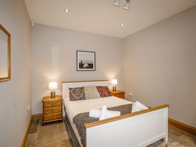 A bedroom with a double bed two bedside tables two lamps a framed picture and a mirror at Family House in Weymouth