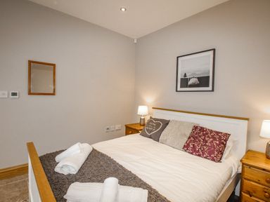 A bedroom with a double bed pillows bedside tables lamps and a framed picture on the wall at Family House in Weymouth