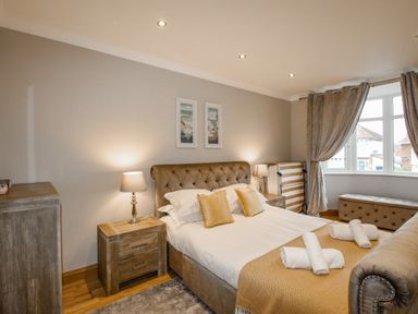 A bedroom with a bed with pillows blankets and rolled towels bedside tables lamps a chest and a window at Family House in Weymouth